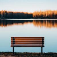 Serene lake view with a wooden bench in the foreground. photo
