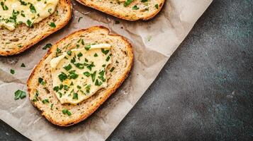 Sliced bread topped with butter and herbs on parchment paper. photo