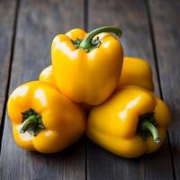 Fresh yellow bell peppers stacked on a wooden surface. photo