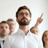 Man in glasses with a focused expression, surrounded by attentive colleagues. photo