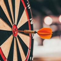 Dart hitting the bullseye on a dartboard with a blurred background. photo