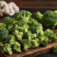 Fresh broccoli on a wooden surface with mushrooms in the background. photo