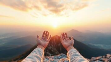 Hands raised towards a beautiful sunrise over mountain peaks. photo