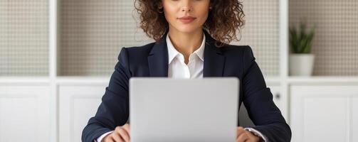 Professional woman working on a laptop in a modern office setting. photo