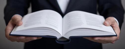 Open book held by a person in a suit against a dark background. photo