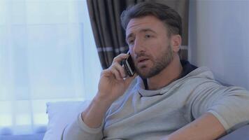 Thoughtful man engaged in a phone conversation at home video