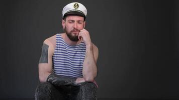 Bored bearded skipper in a sailor outfit against a dark gray backdrop video