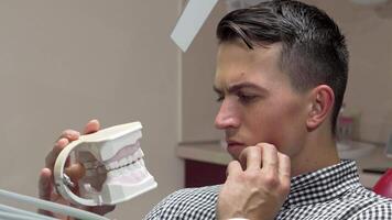 Young man experiencing toothache in dental chair at clinic video