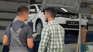 Mechanic and customer shaking hands in a busy garage video