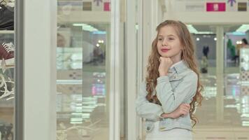 Charming little girl joyfully posing while admiring a fashion store display video