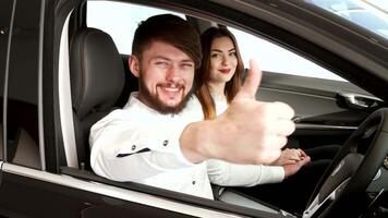 Cheerful couple celebrating their new car with a thumbs-up from the window video