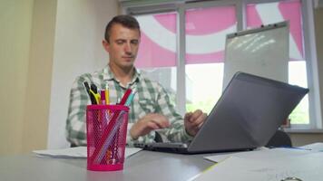 Focused young man studying in a college library, reaching for a pencil in a vibrant cup holder video
