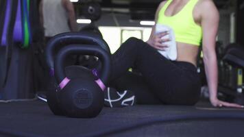 Fitness woman resting after an intense workout, kettlebells in the foreground video