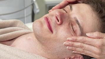 Happy man indulging in a rejuvenating head and face massage at a serene spa video