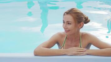 Joyful woman smiling and relaxing in a sparkling swimming pool video