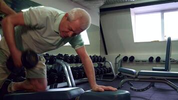 Senior man lifts dumbbell on the bench with focused determination video