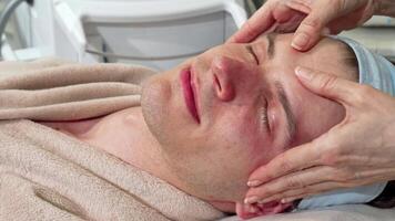 Handsome man enjoying a rejuvenating face massage at a serene spa video