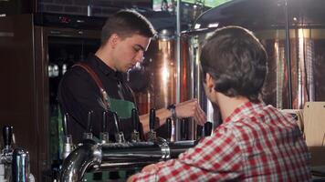 Cheerful bartender pouring a refreshing beer for his customer video