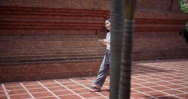 Female tourist enjoys takes photos with mobile phone while strolling around, admiring the peaceful atmosphere and cultural beauty of the place. video