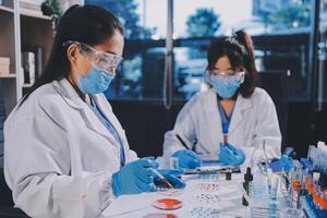 Two women in lab coats and masks working on a project photo