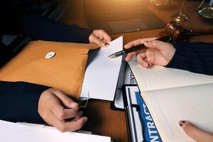 Two people are sitting at a desk with a pen and papers photo