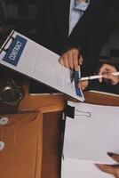 A man in a suit is signing paperwork with a pen photo