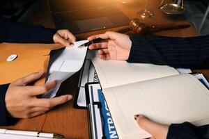 Two business people are sitting at a desk with a pen and paper photo
