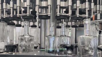 Automated bottling machine filling glass bottles on a modern beverage production line, close-up video