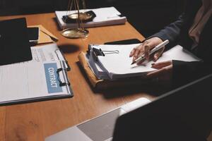 A lawyer is writing on a paper with a laptop photo