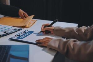 A person signing a contract on a clipboard photo