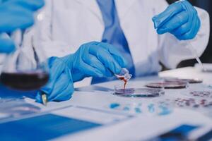 A person in blue gloves and a white lab coat is working on a test tube photo