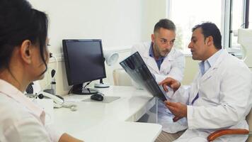 Doctors analyze X-Ray images while consulting a patient in a bright office video