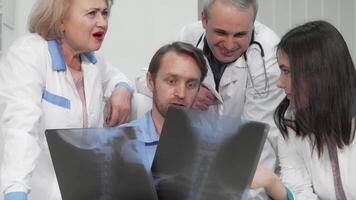 Diverse group of doctors analyzing x-ray scans with focused expressions video