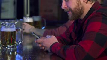 Young man engrossed in texting at a lively pub video