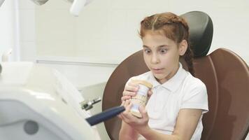 Surprised girl examines an artificial jaw with wide eyes video