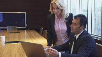 Focused man and woman collaborating on a project while reviewing a laptop video
