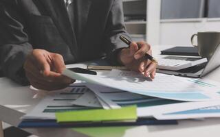 A man in a suit is working on paperwork at a desk photo