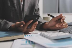 A business person using a calculator and pen to write on a smartphone photo