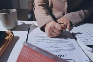 A woman signing a contract with a pen and a calculator photo