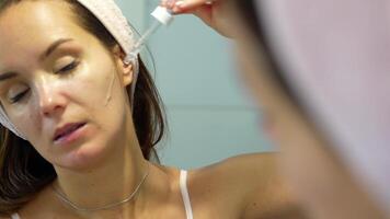 Woman applying facial serum with dropper during skincare routine video