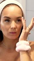 Vertical close-up of woman tapping under-eye area during skincare routine video