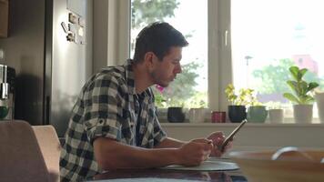 Man eating breakfast while using smartphone. Male looking at phone during breakfast. Concept of social media addiction, distraction, and digital dependency video