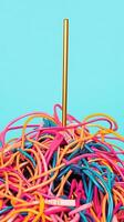 Colorful tangle of network cables with golden straw against blue background embodies technology and connectivity chaos. Deadline approaching photo
