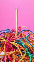 Vibrant tangle of multicolored plastic tubes with golden straw against a bright pink background showcasing colorful abstract art. Deadline approaching photo