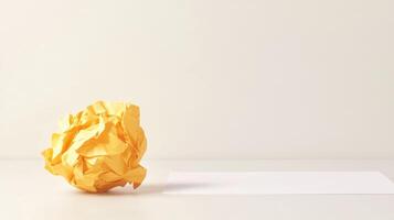 Minimalist workspace with crumpled yellow paper ball and blank sheet on desk. Symbolism of fresh starts photo