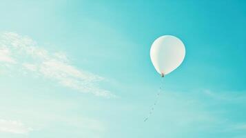 White balloon floating in clear blue sky with wispy clouds. Symbolism of fresh starts photo