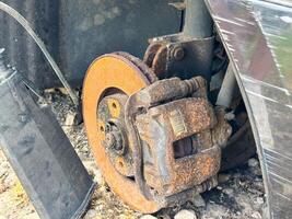 Rusted brake caliper and disc from a car showing severe corrosion on the braking system, with exposed suspension components and wheel hub assembly photo