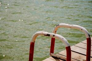 Tranquil lake dock scene with weathered metal handrails for relaxation and inspiration. Weekend concept near the forest and lake photo