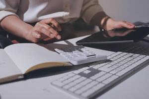 A woman is using a calculator and a tablet on a desk photo