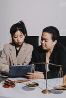 Two businesswomen in suits sitting at a table with a tablet and scales photo